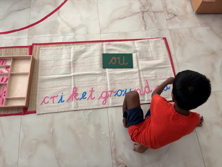 A child builds words with a movable alphabet on a floor mat.