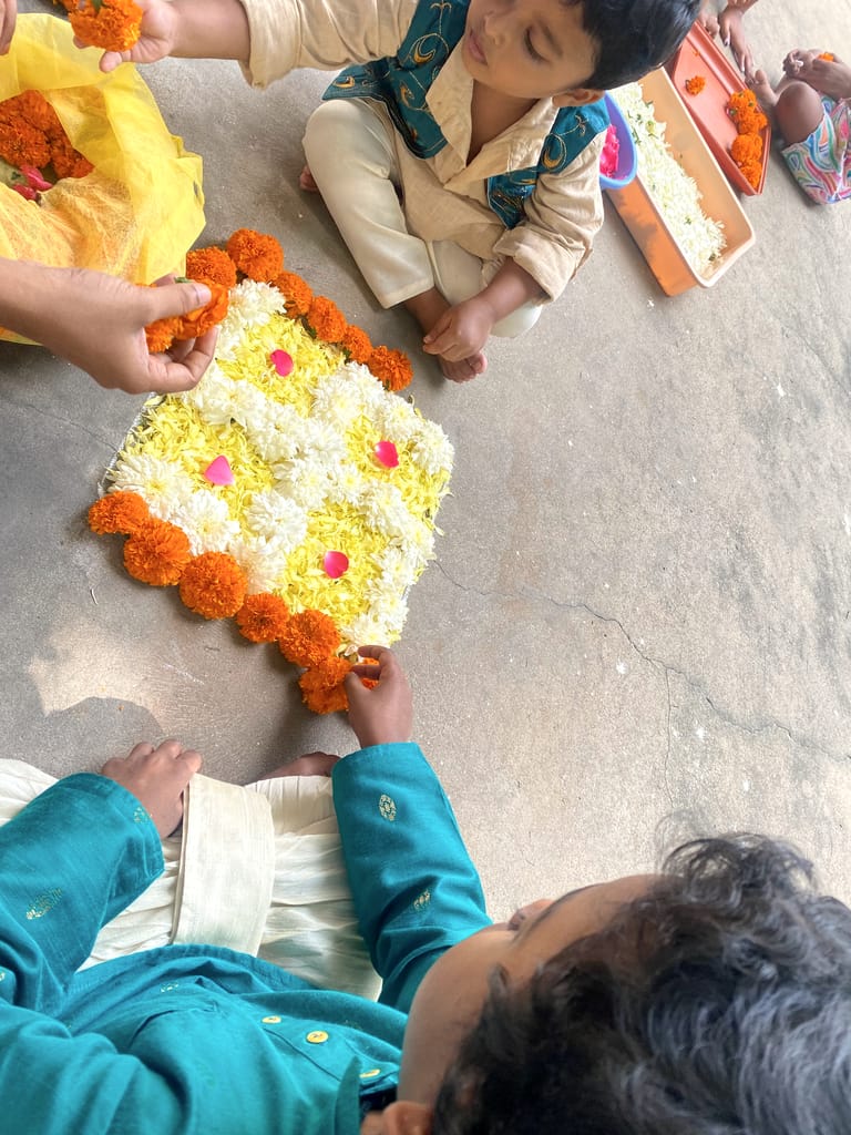 Children arrange colourful flowers in a circular pattern during a celebration.