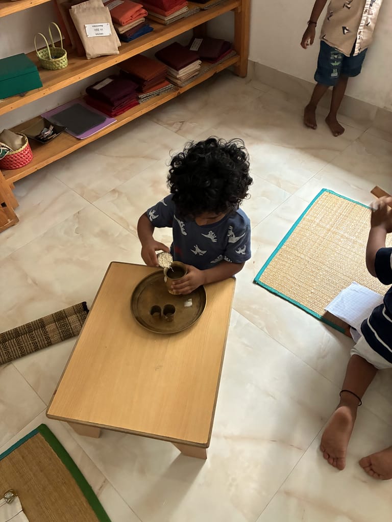 Seen from above, a child polishes a brass plate at a low wooden table.